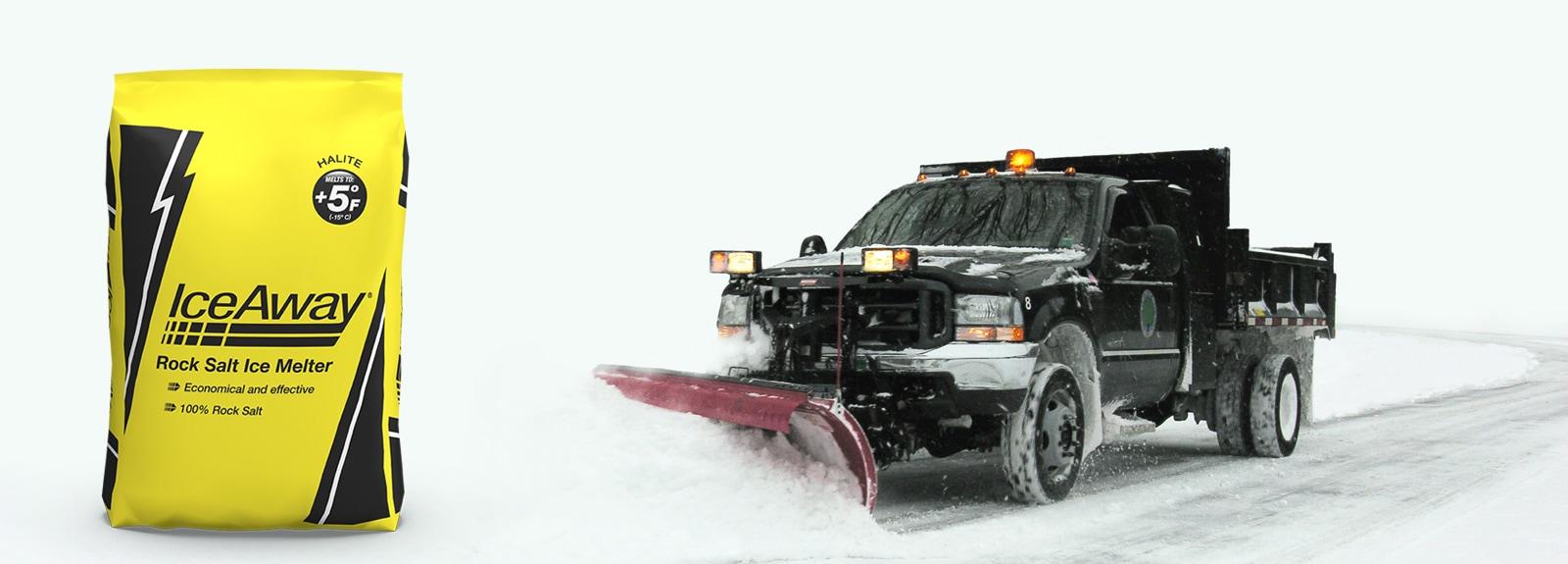 Yellow bag of IceAway rock salt ice melter next to a truck with a snow plow attachment moving snow