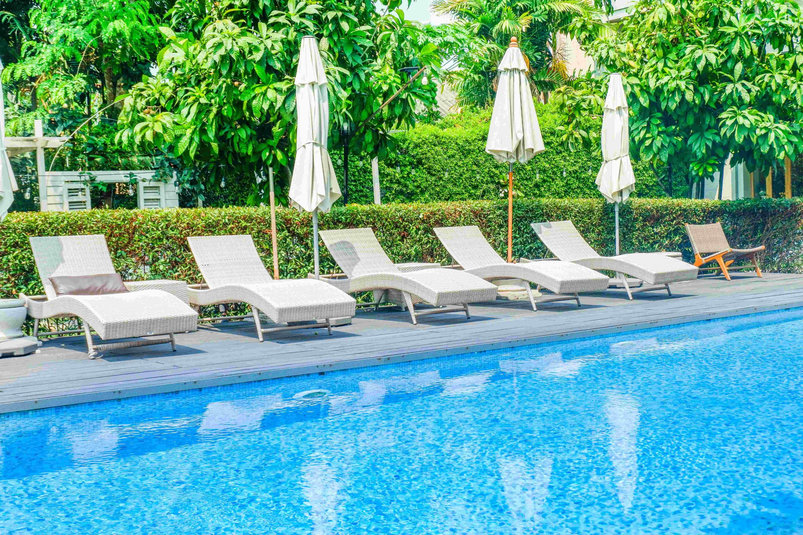 A line of pool lounge chairs and umbrellas by a hotel saltwater pool.
