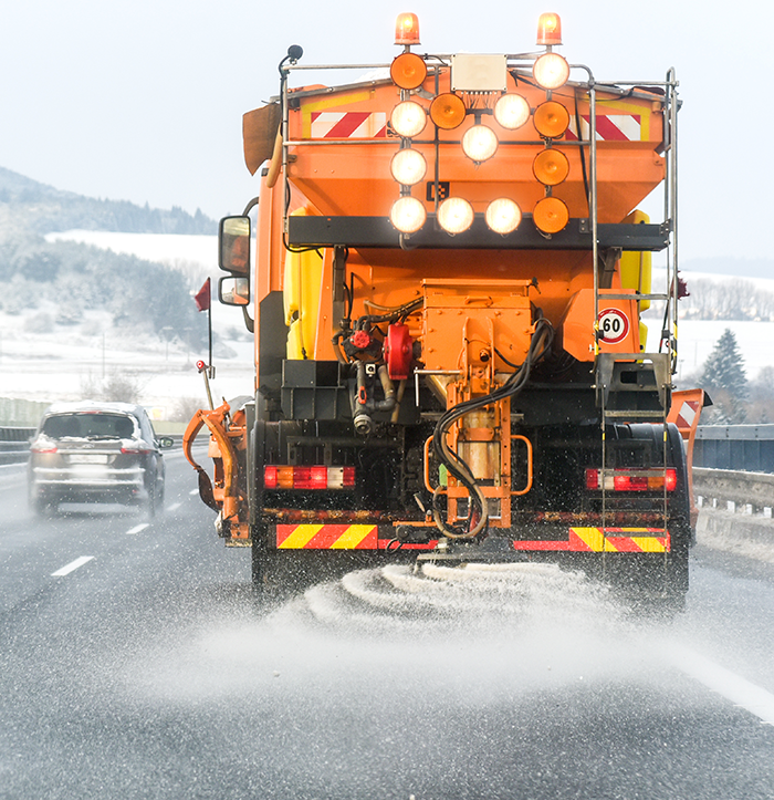 A road salt truck spreading deicing salt on the highway.